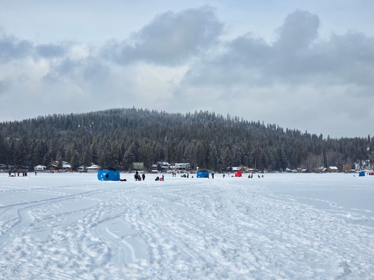 Ice fishing tents and families on snowy ice